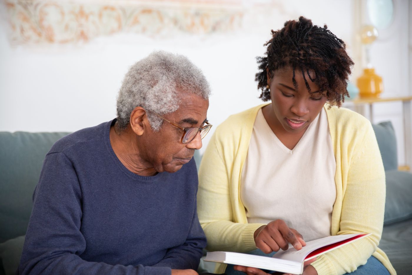 A caregiver reading with an older adult; illustrative photo